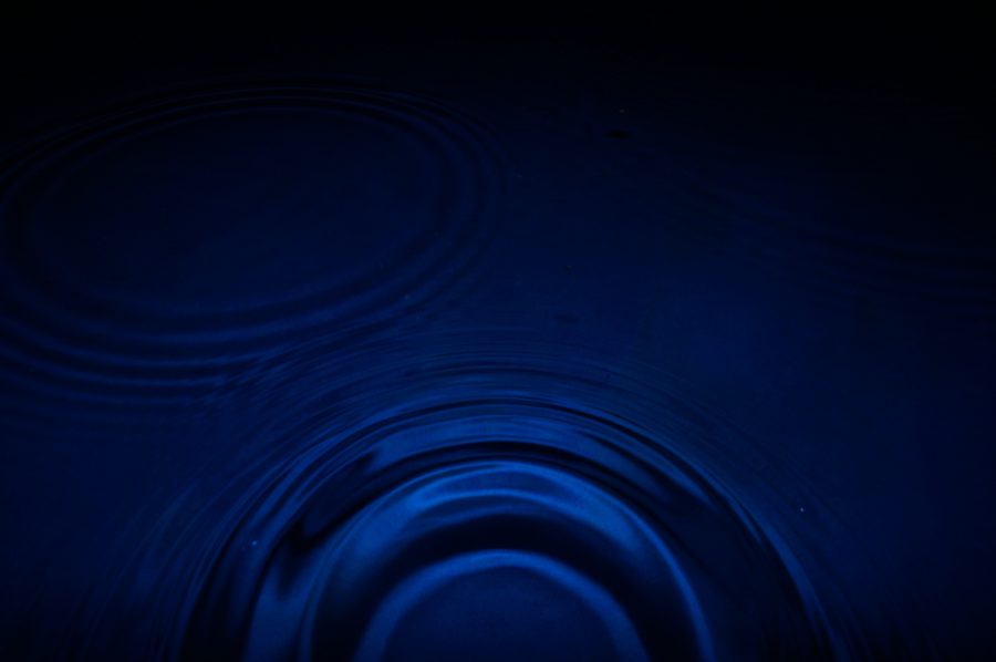 Two faint ripples meeting on dark, still water